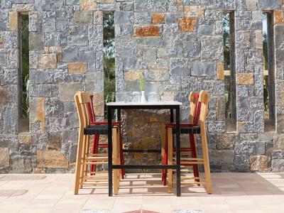 Tavolo all'aperto con sedie davanti a un muro di pietra al sole.