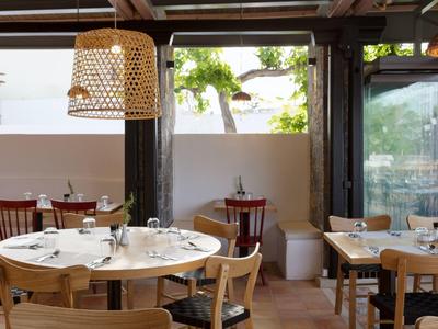 Accogliente area pranzo dell'hotel con tavoli rotondi e quadrati in legno apparecchiati, illuminazione calda.