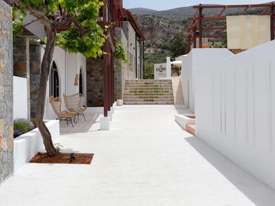 Terraza blanca brillante con escaleras y árbol en un entorno mediterráneo soleado.