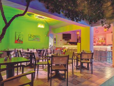 Bright green and yellow outdoor dining area with chairs and tables under trees.