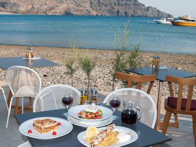 Tavolo con cibo e bevande sulla spiaggia con vista sul mare e una barca.