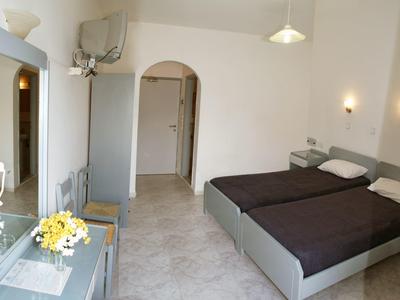 Camera d'hotel semplicemente arredata con due letti singoli, pavimento spazioso e pareti chiare.