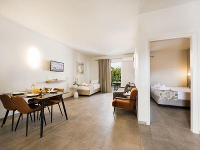 Zona giorno e pranzo luminosa con mobili moderni e accesso a una camera da letto