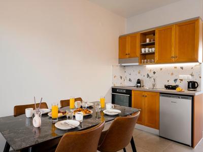 Area cucina moderna con armadietti in legno, tavolo da pranzo e colazione apparecchiata in un appartamento vacanze.