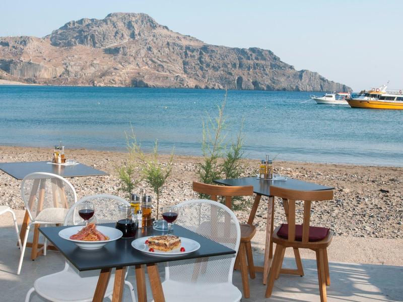 Ristorante sulla spiaggia con tavoli, sedie, snack e vista sul mare e le scogliere