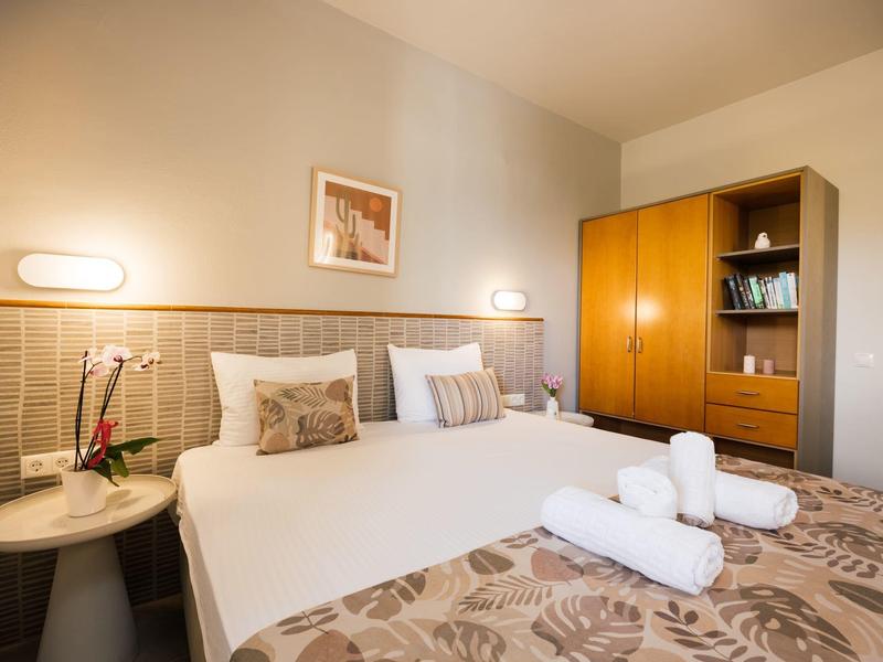 Camera d'hotel accogliente con letto grande, comodino, armadio e illuminazione decorativa.