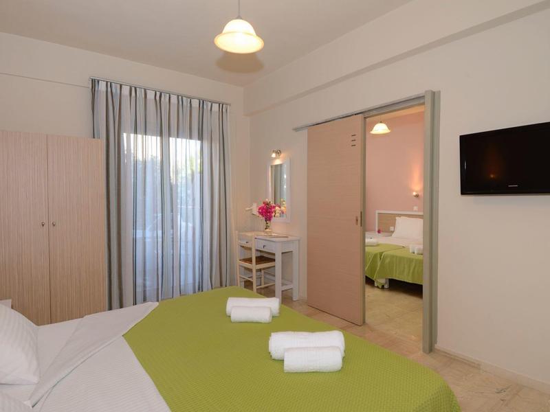 Camera d'hotel accogliente con letto matrimoniale, copriletto verde e vista sulla stanza adiacente.