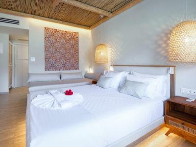 Ein weißes, modern eingerichtetes Schlafzimmer mit Doppelbett, Nachtisch und hängenden Lampen.