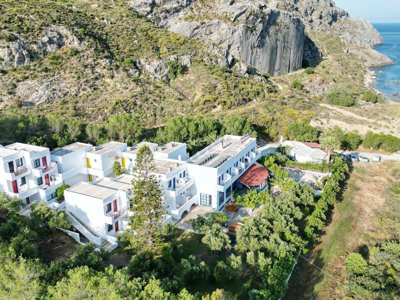 Villenanlage mit weißen Häusern am Hang, umgeben von grüner Vegetation und Blick auf das blaue Meer.