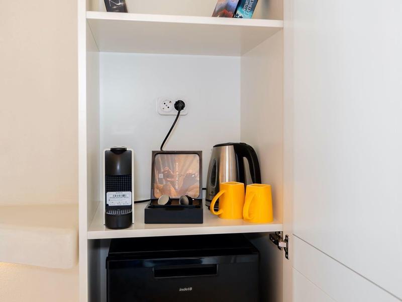 Küchenschrank mit Kaffeemaschine, Wasserkocher, Tassen und Minikühlschrank.