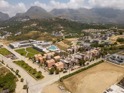 Veduta aerea di un resort con più edifici, piscine e montagne sullo sfondo.