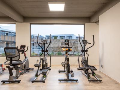 Gimnasio moderno con cuatro máquinas de ejercicio y gran ventana con vista al exterior.