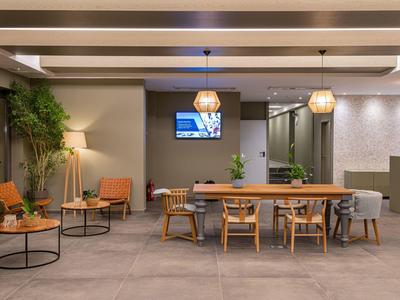 Area lounge moderna dell'hotel con tavoli, sedie e atmosfera rilassata.