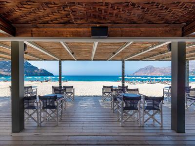 Bar sulla spiaggia con terrazza in legno, tavoli e sedie con vista sul mare e sulla spiaggia