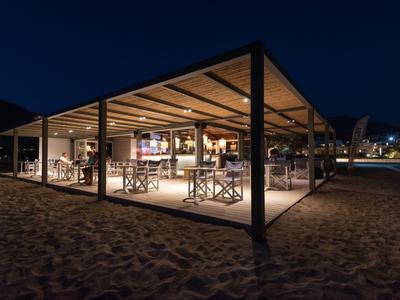 Padiglione sulla spiaggia illuminato con posti a sedere di notte, circondato dalla sabbia.