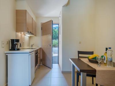 Angolo cottura compatto con macchina da caffè, frigorifero e tavolo da pranzo in una stanza luminosa.