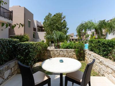 Terrazza con tavolo e sedie, circondata da muri in pietra e piante verdi, in un villaggio turistico.