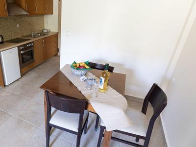 Un piccolo angolo pranzo con un tavolo di legno, due sedie e un angolo cottura sullo sfondo.