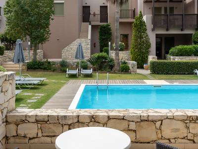 Vista de una piscina con tumbonas y sillas en una terraza de hotel.
