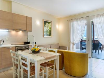 Sala da pranzo luminosa con mobili in legno, tavolo bianco, divano giallo e accesso al balcone