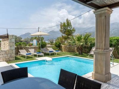 Area piscina moderna con lettini e tavolo esterno con sfondo montano.