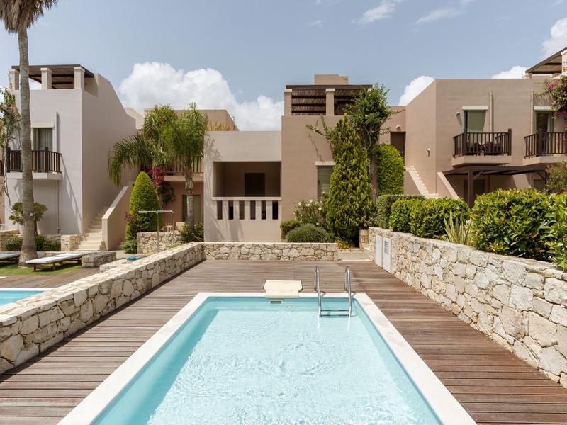 Piscina d'hotel moderna con terrazza in legno e architettura mediterranea alla luce del sole.
