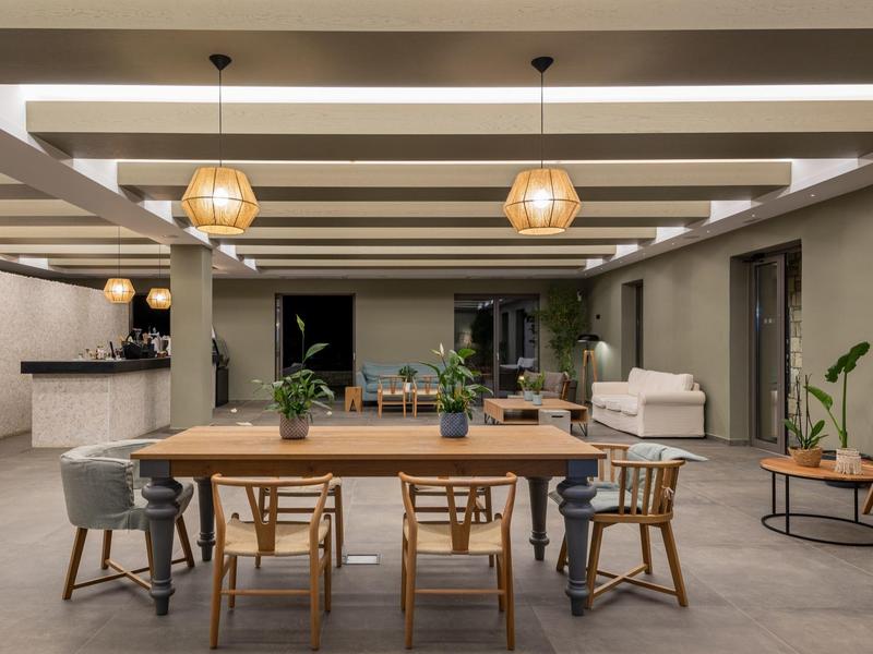 Area comune arredata modernamente con tavolo in legno, sedie e luci sospese.