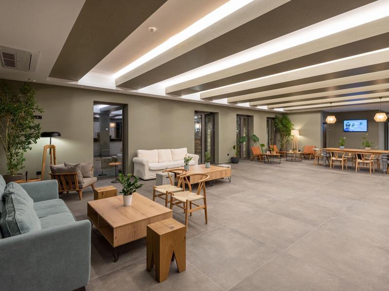 Area lounge dell'hotel moderna e spaziosa con divani, tavoli e luce calda.