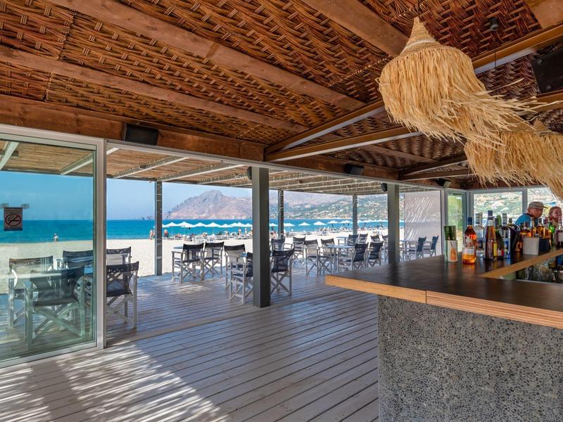 Bar sulla spiaggia con pavimento in legno e vista sulla spiaggia sabbiosa e sul mare