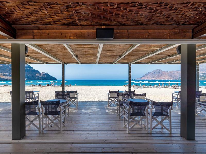 Bar sulla spiaggia con terrazza in legno, tavoli e sedie con vista sul mare e sulla spiaggia