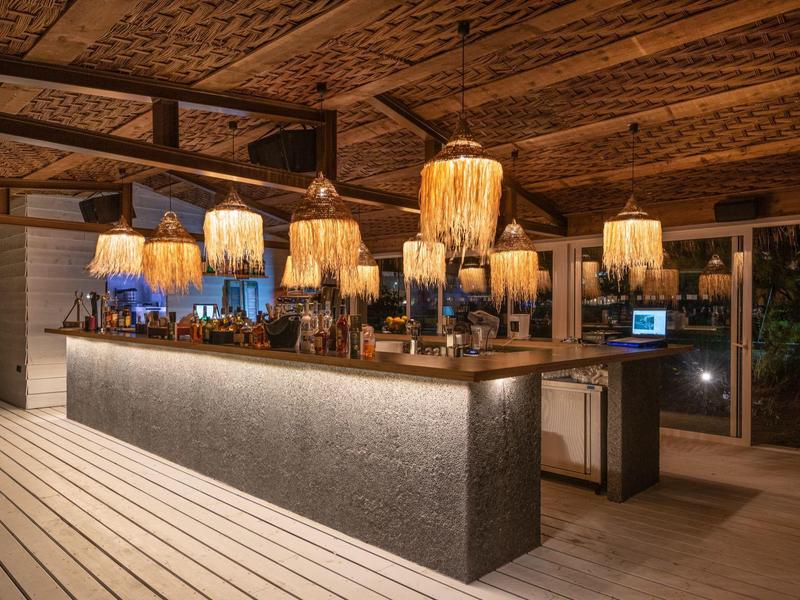 Bar dell'hotel moderno con bancone illuminato e lampade sospese eleganti di notte.