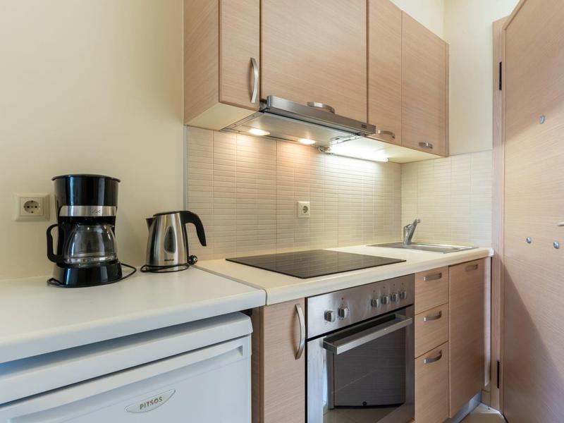 Piccola cucina moderna con macchina per il caffè, bollitore e piano cottura in una camera d'hotel.