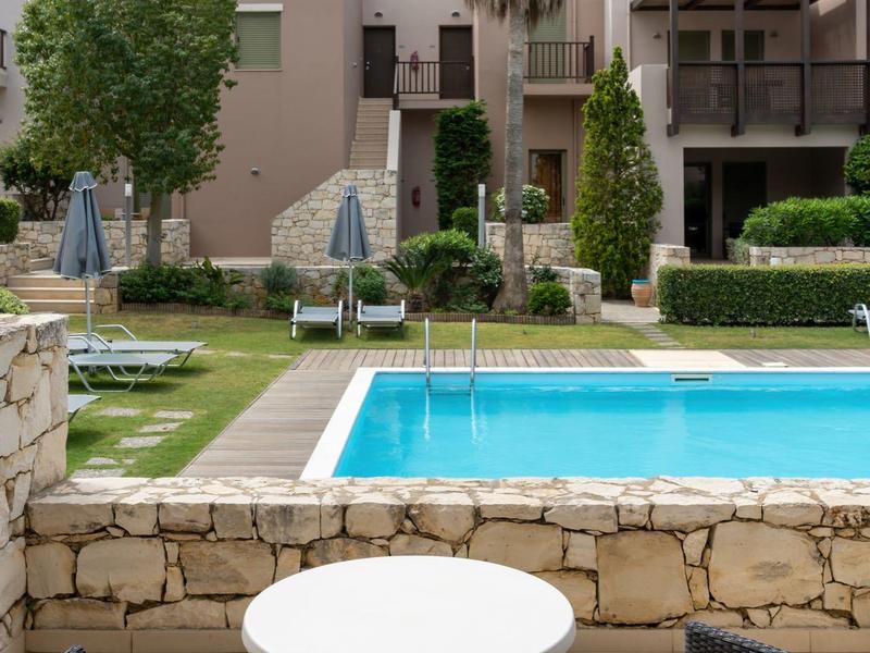 Piscina esterna moderna con area salotto e palme in un giardino dell'hotel.