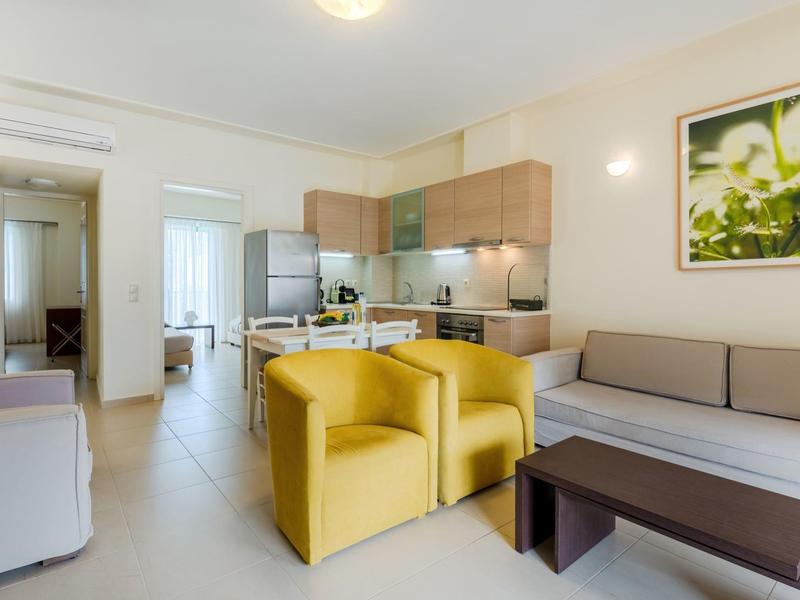 Soggiorno moderno con poltrone gialle, divano e cucina aperta in appartamento luminoso.