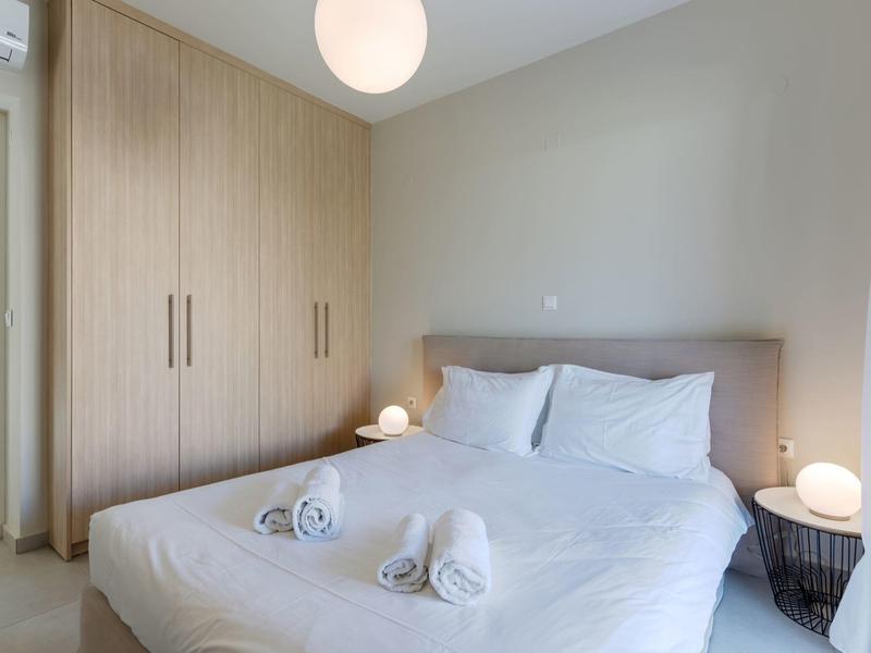 Camera da letto con letto grande, biancheria bianca, grande armadio e due lampade da comodino.