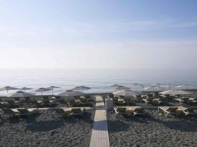 Plage vide avec transats et parasols, mer calme sous un ciel clair.