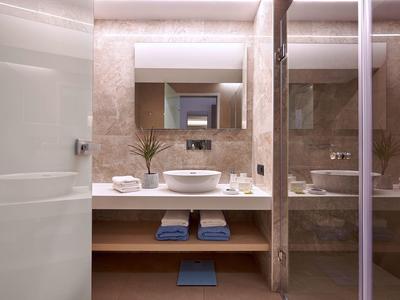 Salle de bain d'hôtel moderne avec vasque ronde, miroir et serviettes.