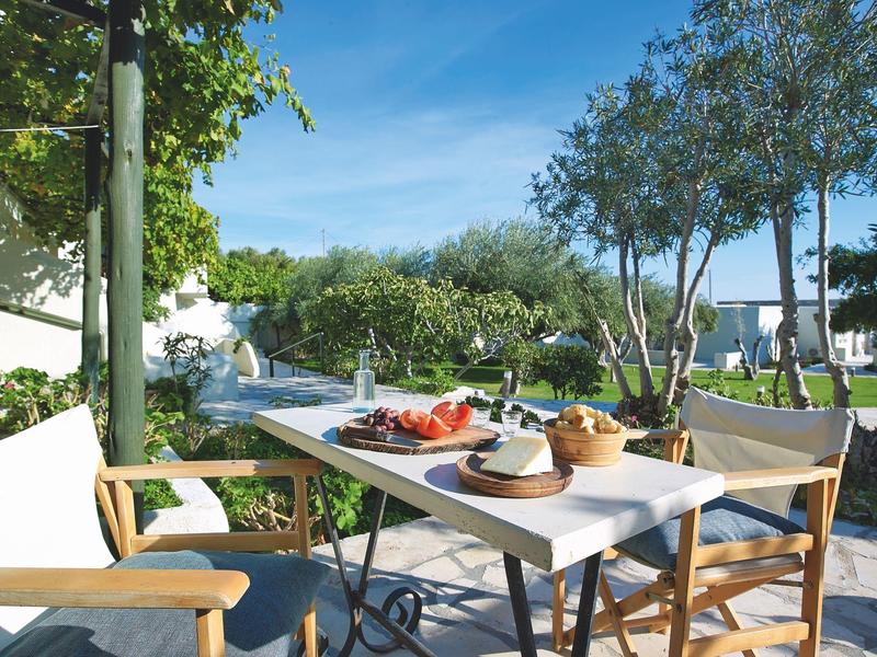 Une table dressée avec de la nourriture et des boissons dans un jardin d'hôtel par temps ensoleillé.