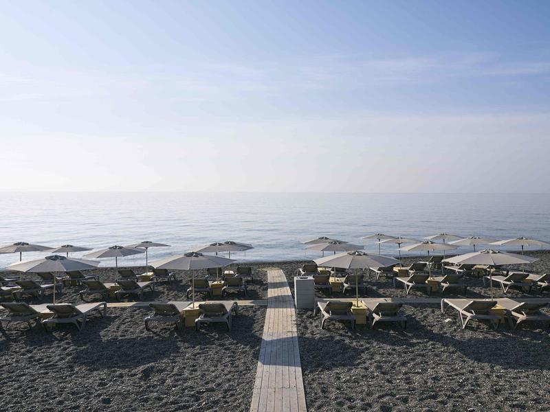 Plage vide avec transats et parasols, mer calme sous un ciel clair.