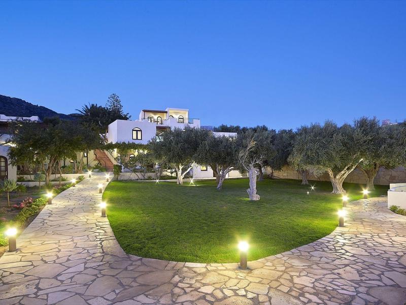 Sentier de jardin éclairé avec pelouse soignée et oliviers sous ciel clair
