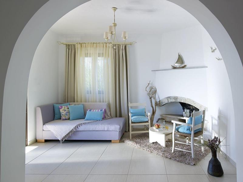 Coin salon lumineux avec canapé, chaises et tapis rond derrière un arc