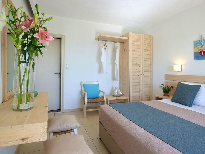 Chambre moderne avec lit, armoire, chaise et fleurs fraîches sur la table.