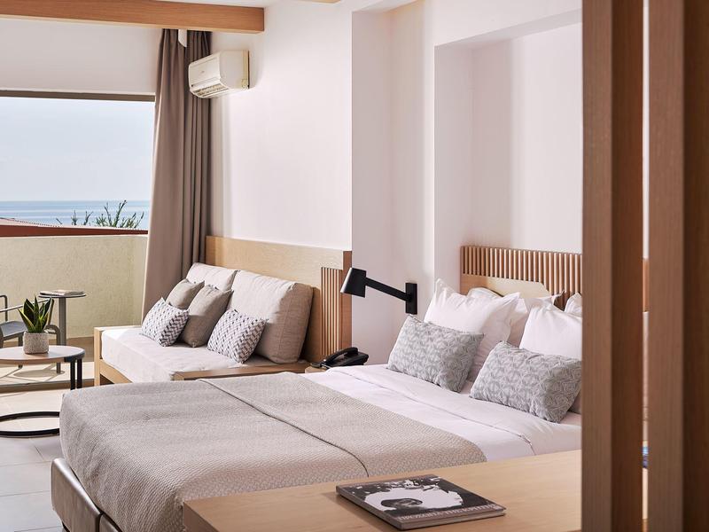 Chambre d'hôtel moderne avec lit double et balcon avec vue sur la mer.