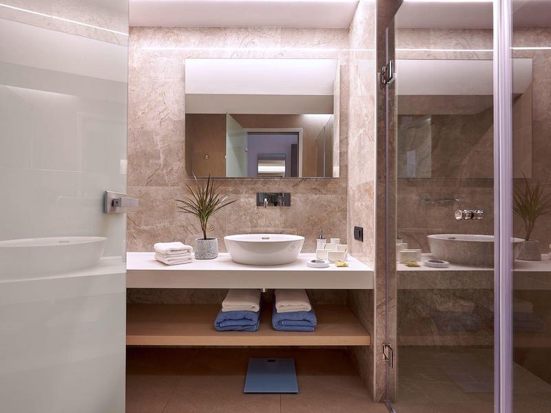 Salle de bain d'hôtel moderne avec vasque ronde, miroir et serviettes.