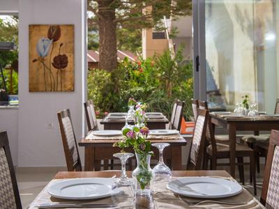 Ristorante elegante con tavoli apparecchiati e vista sulle piante verdi esterne.