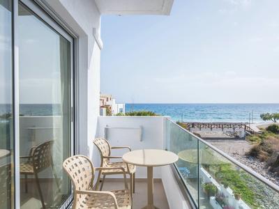 Balcone con due sedie e un tavolo con vista sul mare in una giornata di sole.