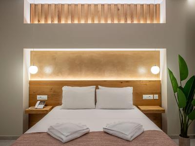 Nowoczesny pokój hotelowy z podwójnym łóżkiem, miękkimi poduszkami, ciepłym światłem i zieloną rośliną.