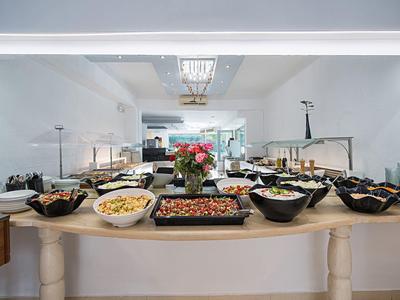 Buffet mit verschiedenen Salaten in schwarzen Schalen auf einem hellen Holztisch in hellem Raum.