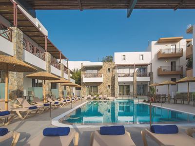 Piscina esterna moderna con lettini tra due edifici sotto un cielo azzurro.