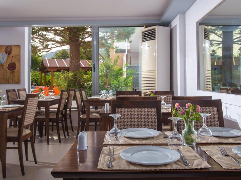 Hell eingerichteter Speiseraum mit großen Fenstern, gedeckten Tischen und Blick ins Grüne.